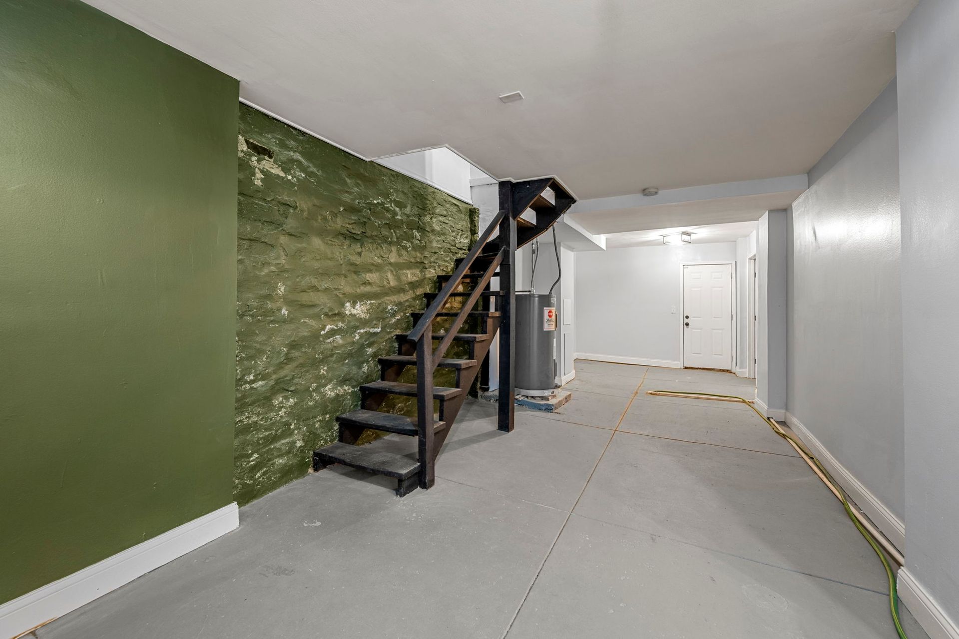 Basement interior with stairs, green and gray walls, and a white door.