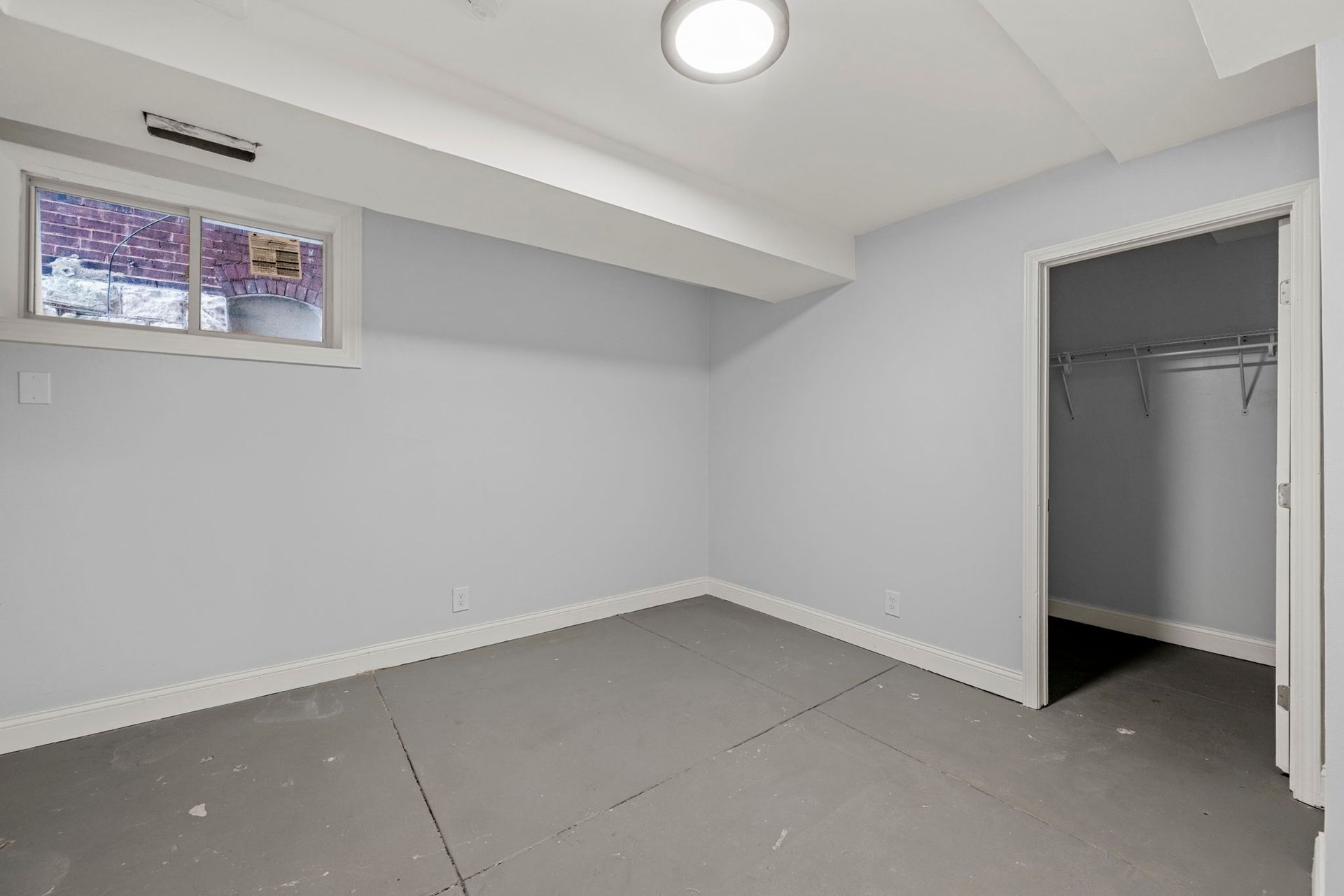Empty gray room with a window, closet, and overhead light.