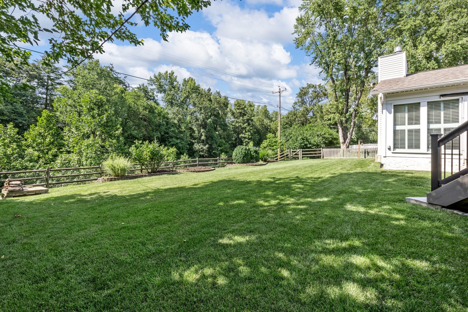 A large lush green yard with a house in the background.