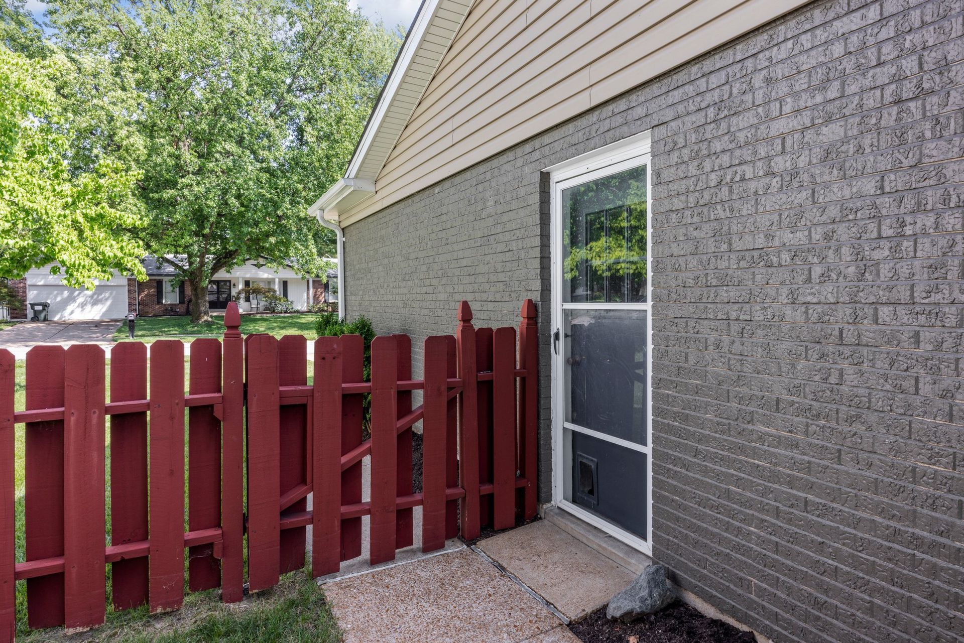 A brick house with a red fence and a sliding glass door.