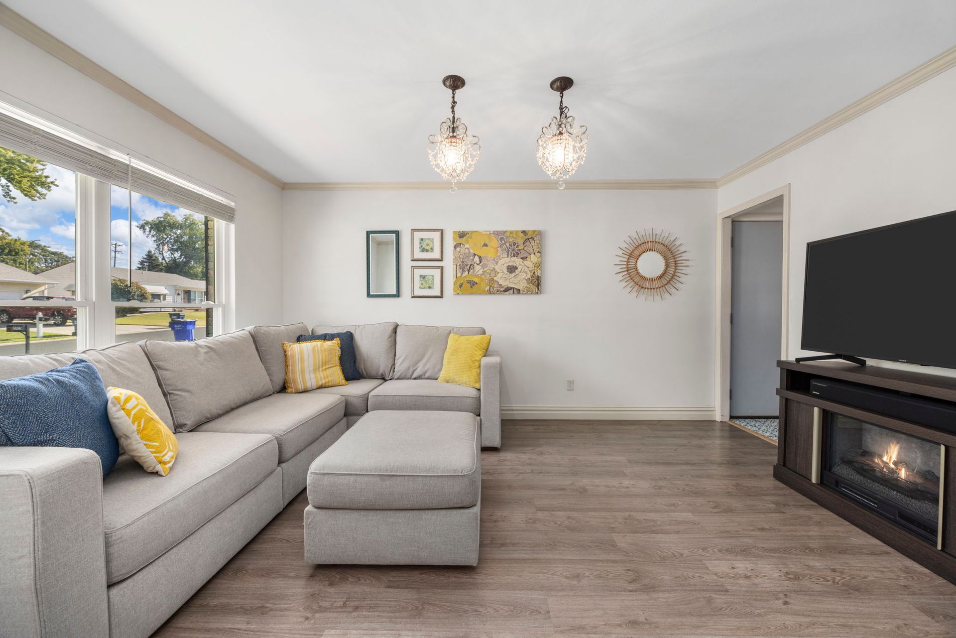 Living room with gray sectional, TV over fireplace, and artwork.