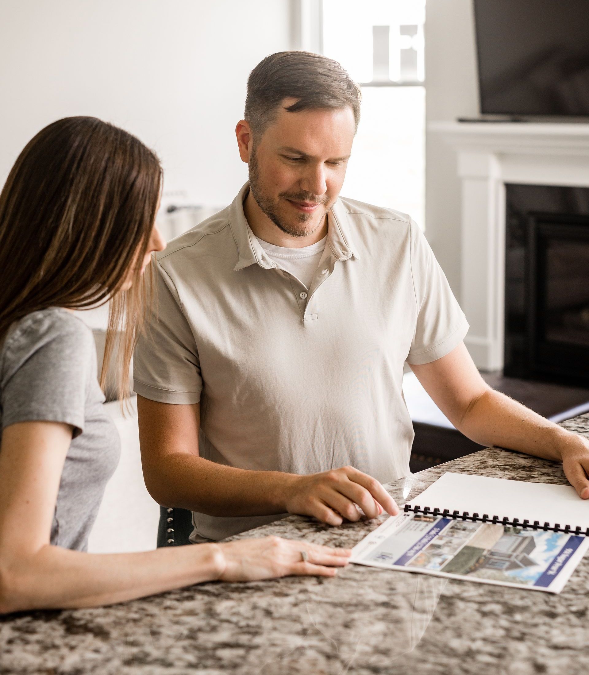 Woman and man looking at papers at a countertop, possibly a home.