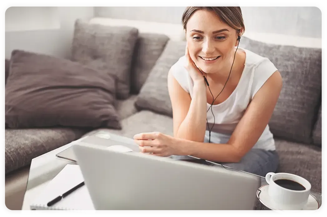 A woman is sitting on a couch using a laptop computer.