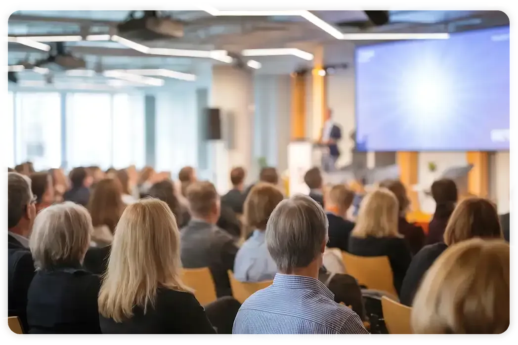 A group of people are sitting in a conference room watching a presentation.