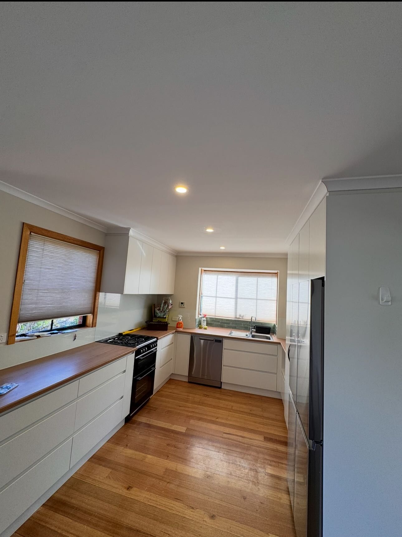 Kitchen with white cabinets, wooden floor, and stainless steel appliances.