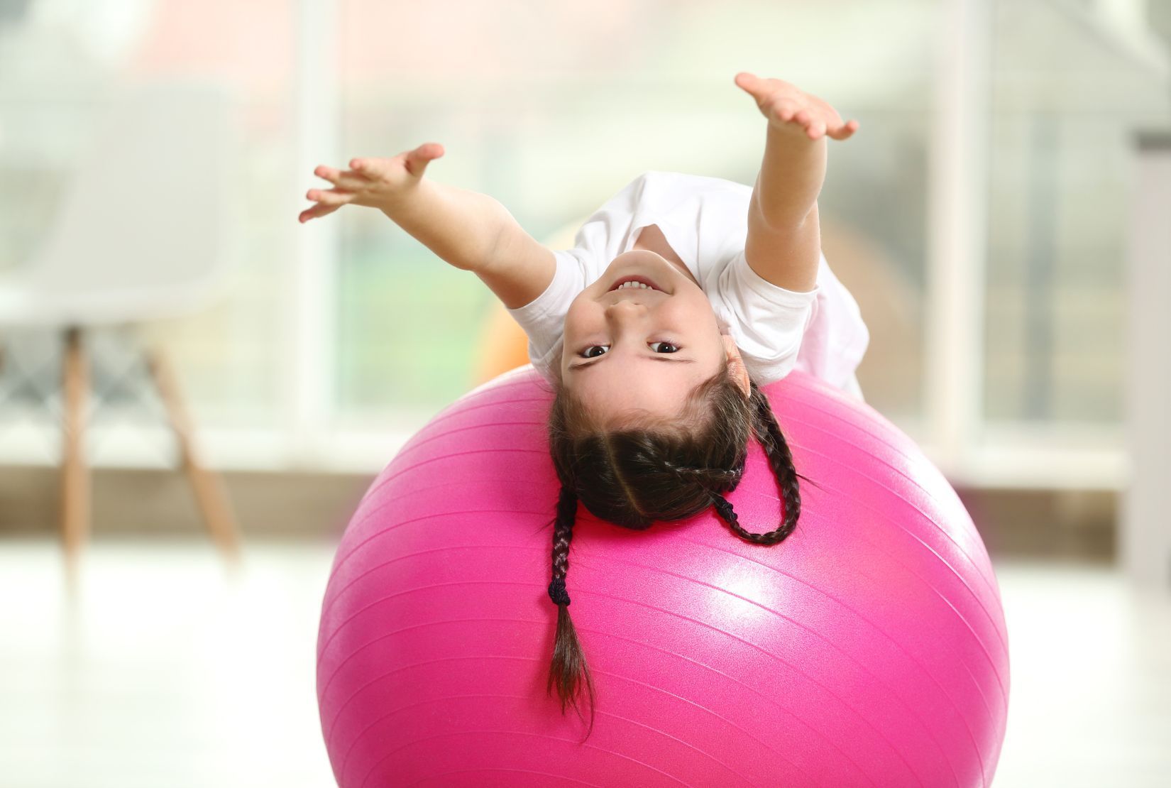 A group of children are sitting in a circle on a colorful parachute.