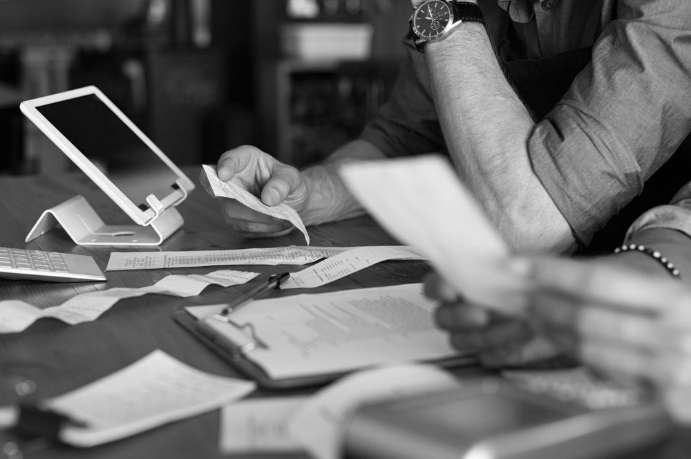 A group of people are sitting at a table looking at papers and a tablet.