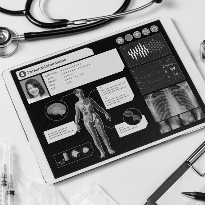 Tablet displaying medical data, stethoscope, syringe, and pen on a white surface.