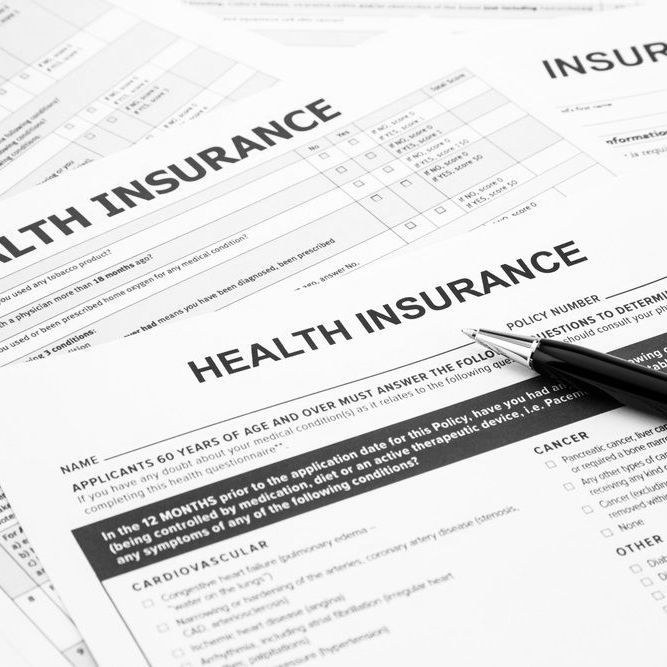 Health insurance application forms with a pen on top.