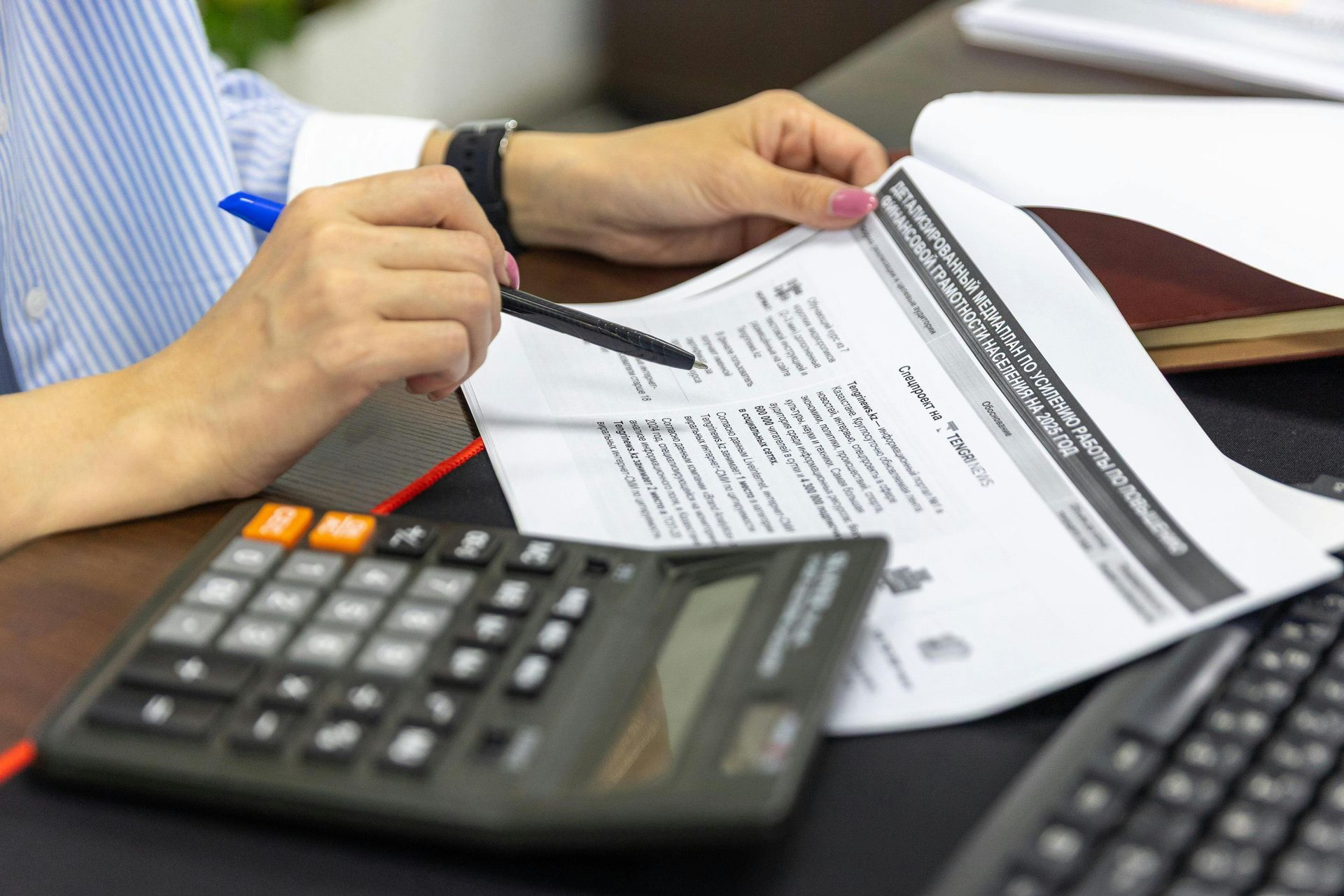 Person reviewing a printed bill with a calculator on a desk, in a business setting