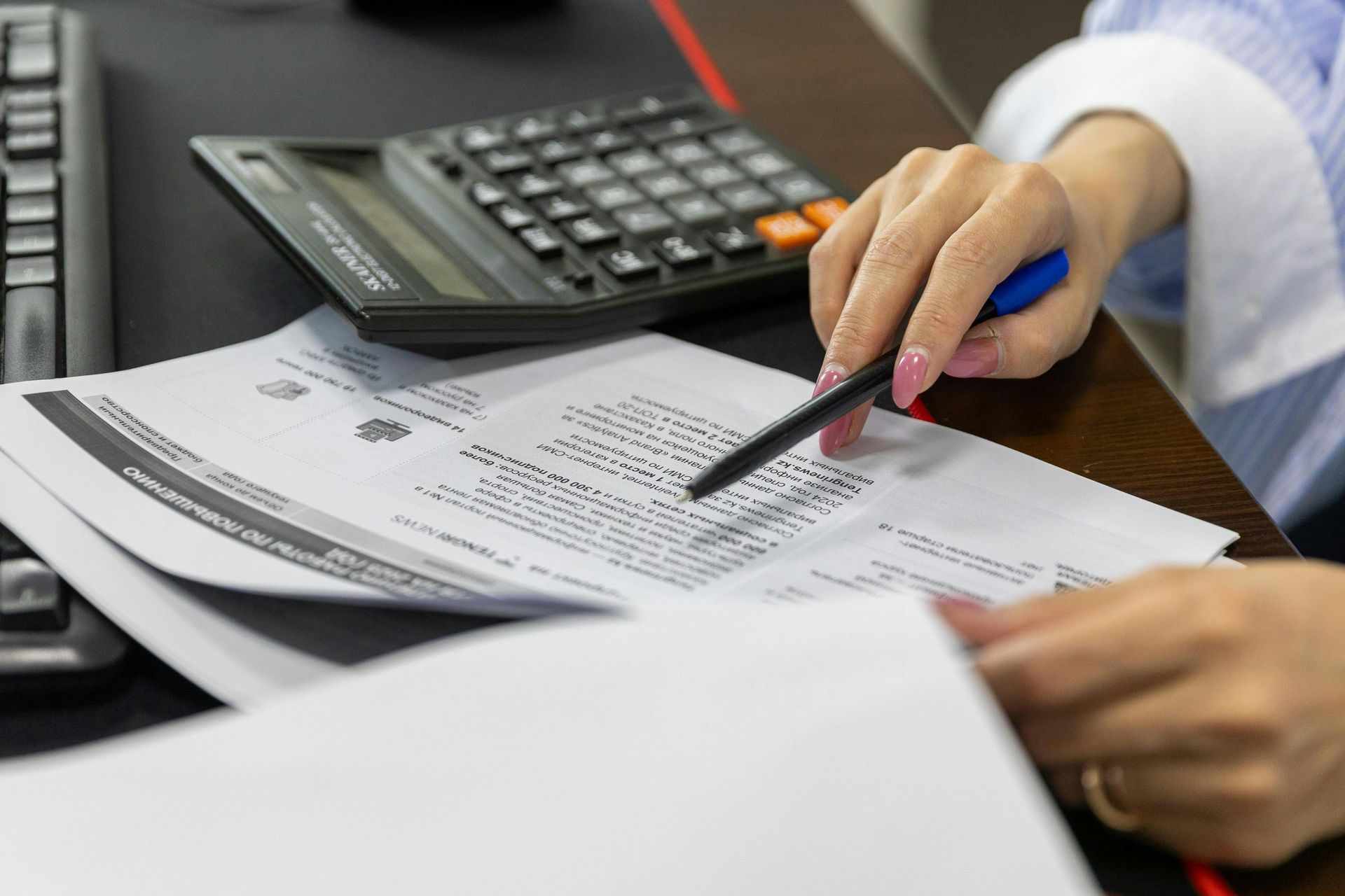 Person reviewing a financial document with a calculator on a desk