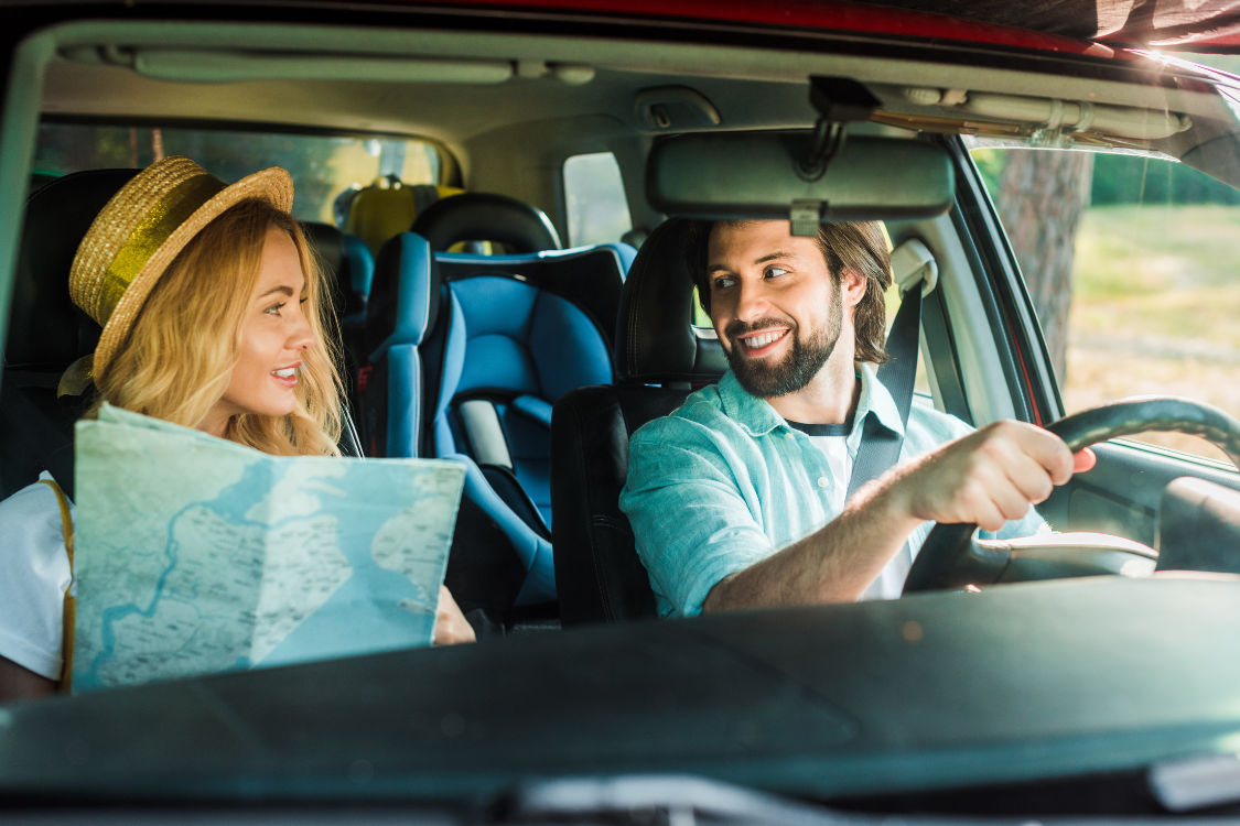A man and a woman are sitting in a car looking at each other.