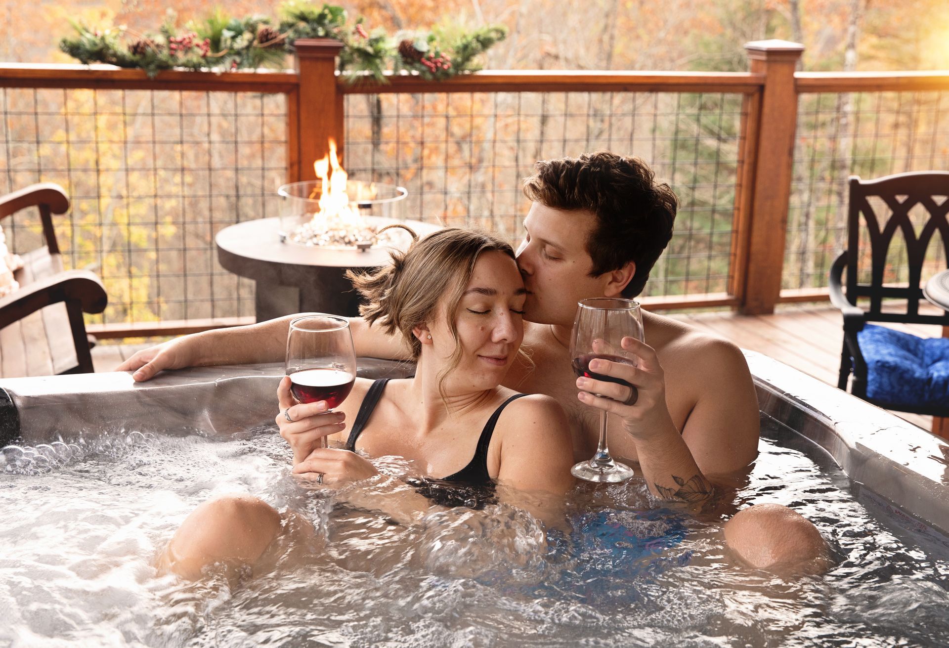 A man and a woman are sitting in a hot tub holding wine glasses.