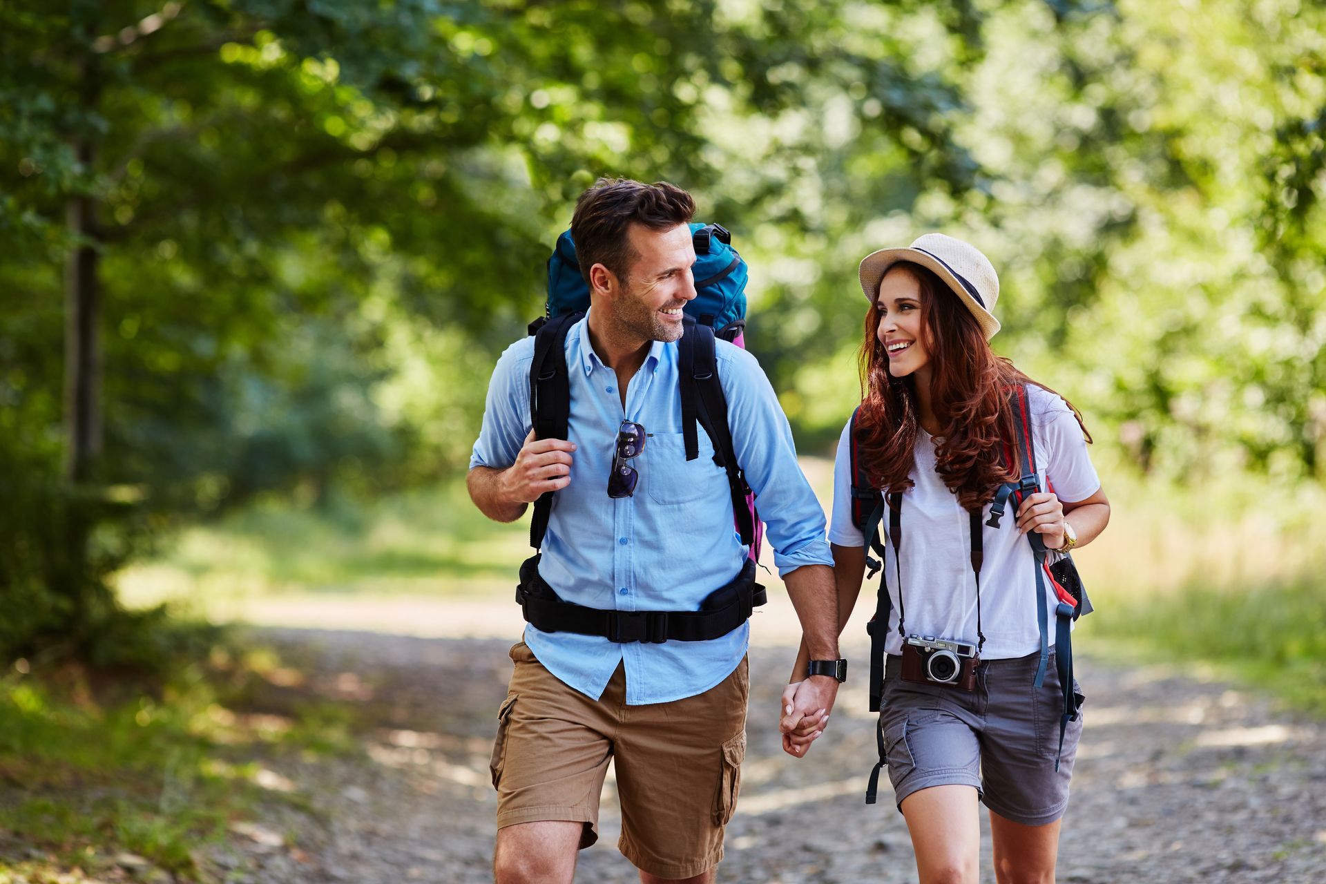 A man and a woman are walking down a dirt path holding hands.