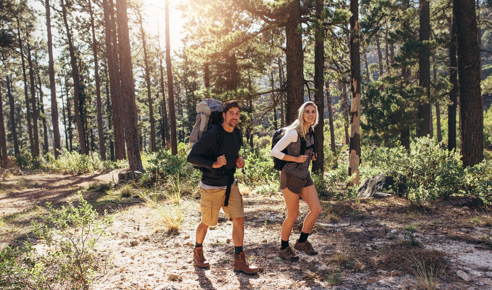 A man and a woman are hiking through a forest.
