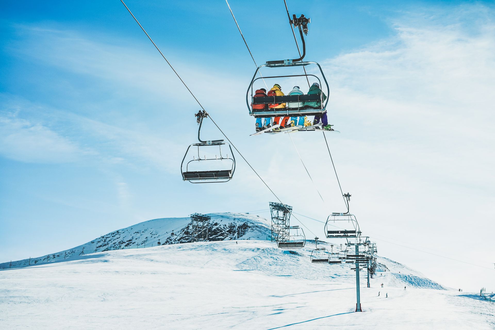 A group of people are riding a ski lift on top of a snow covered mountain.