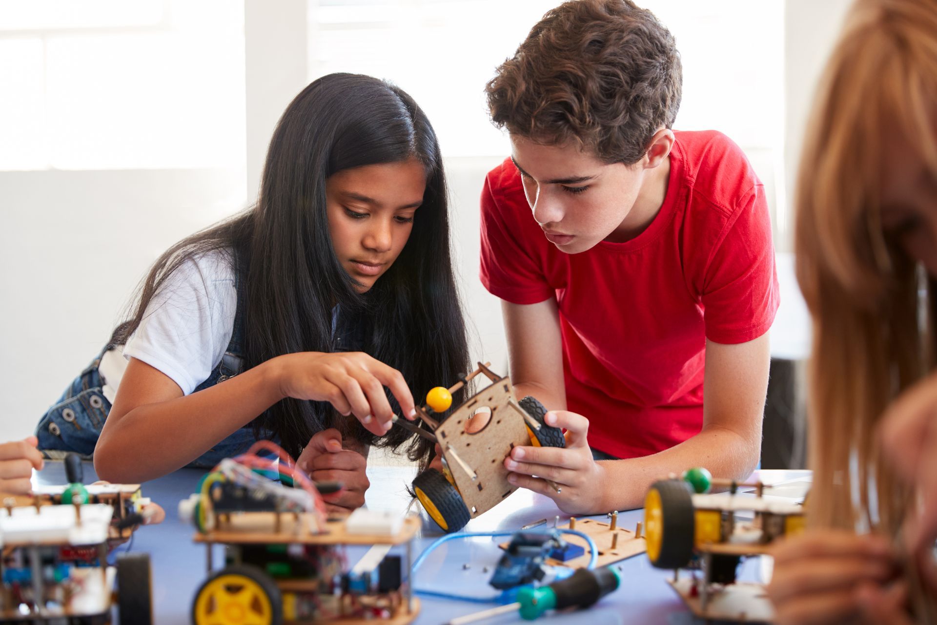 A boy and a girl are working on a robot together.