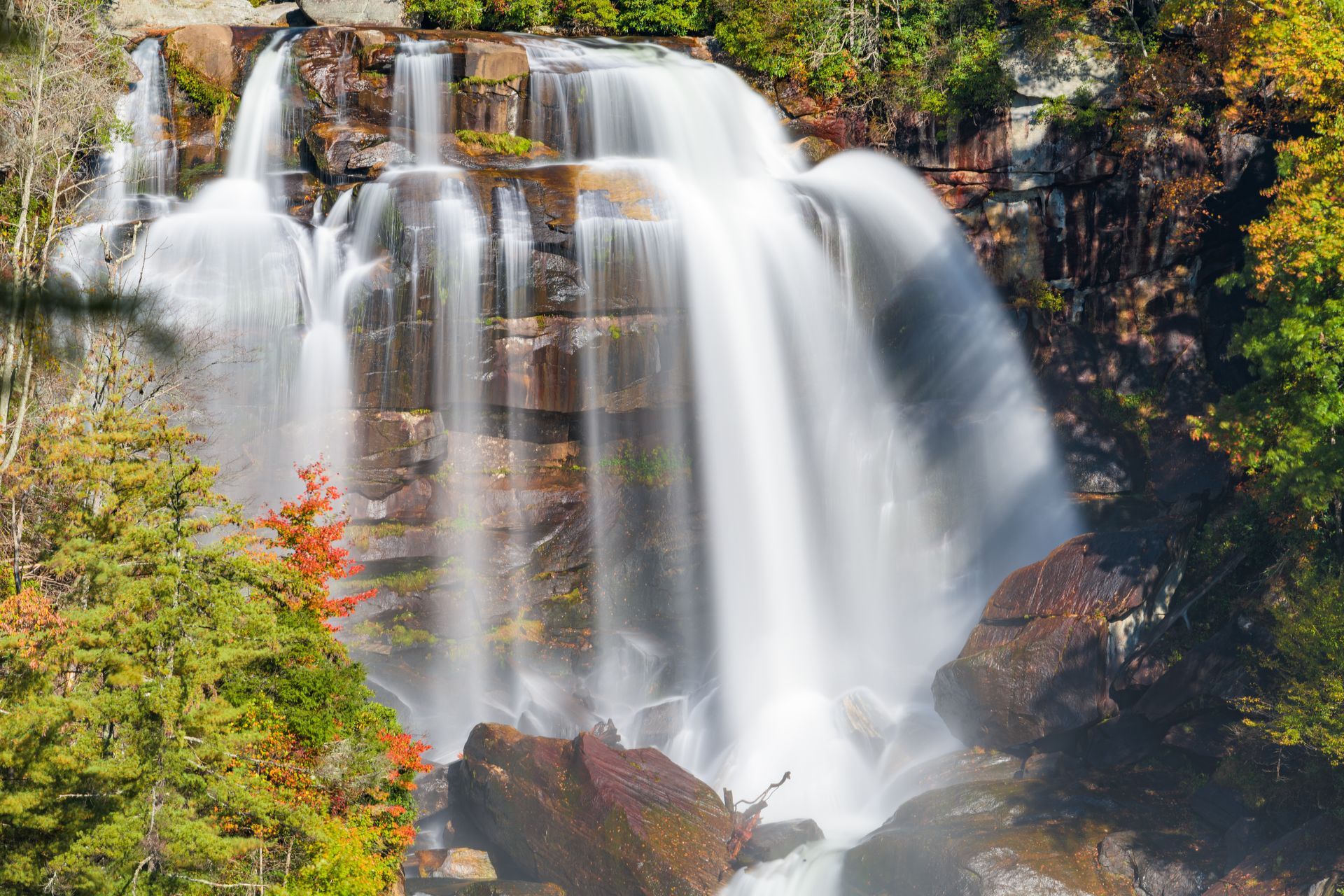 A waterfall is surrounded by trees and rocks in the middle of a forest.