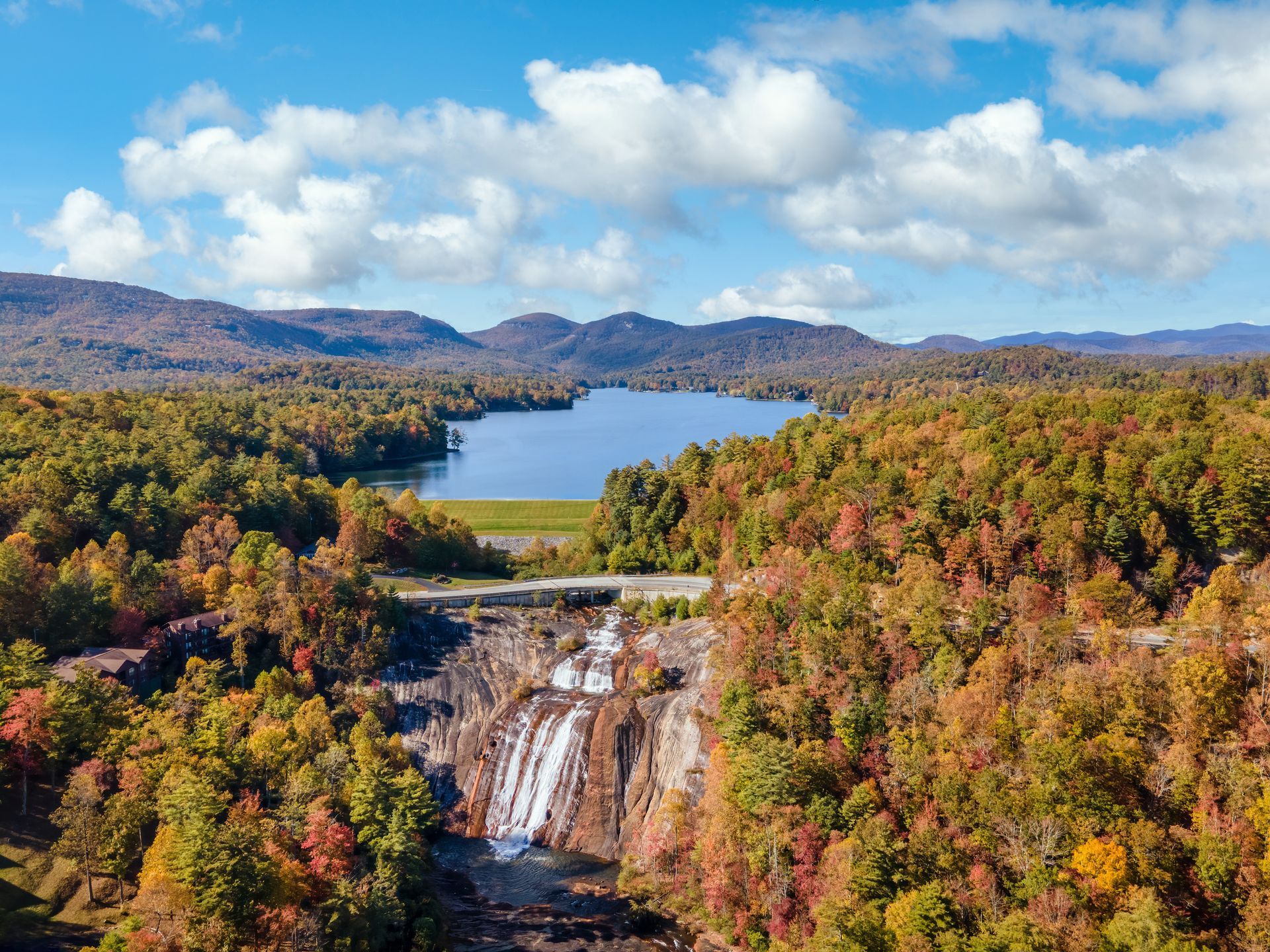 An aerial view of a waterfall surrounded by trees and a lake.