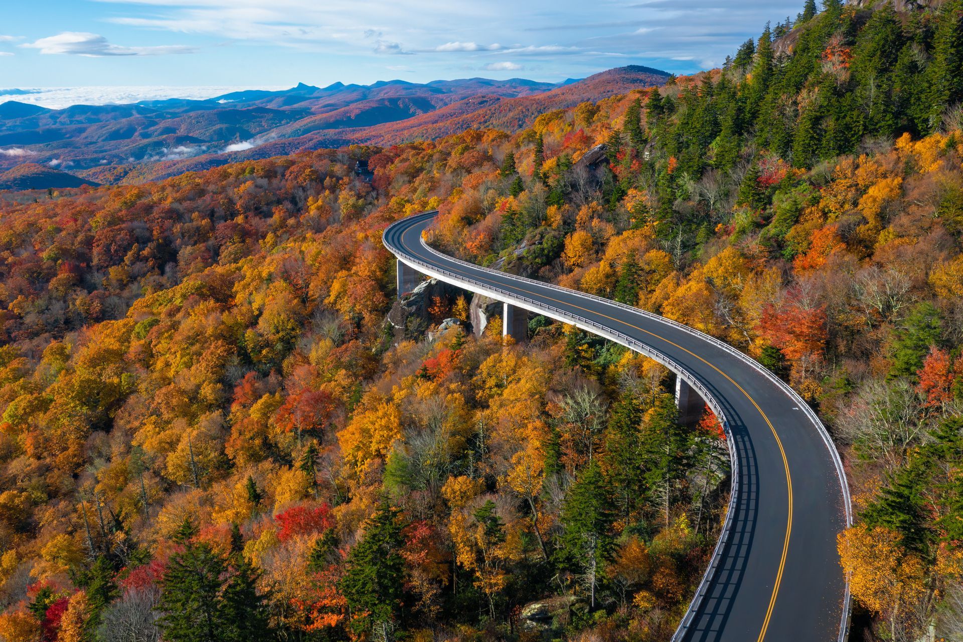 An aerial view of a highway surrounded by trees in autumn.