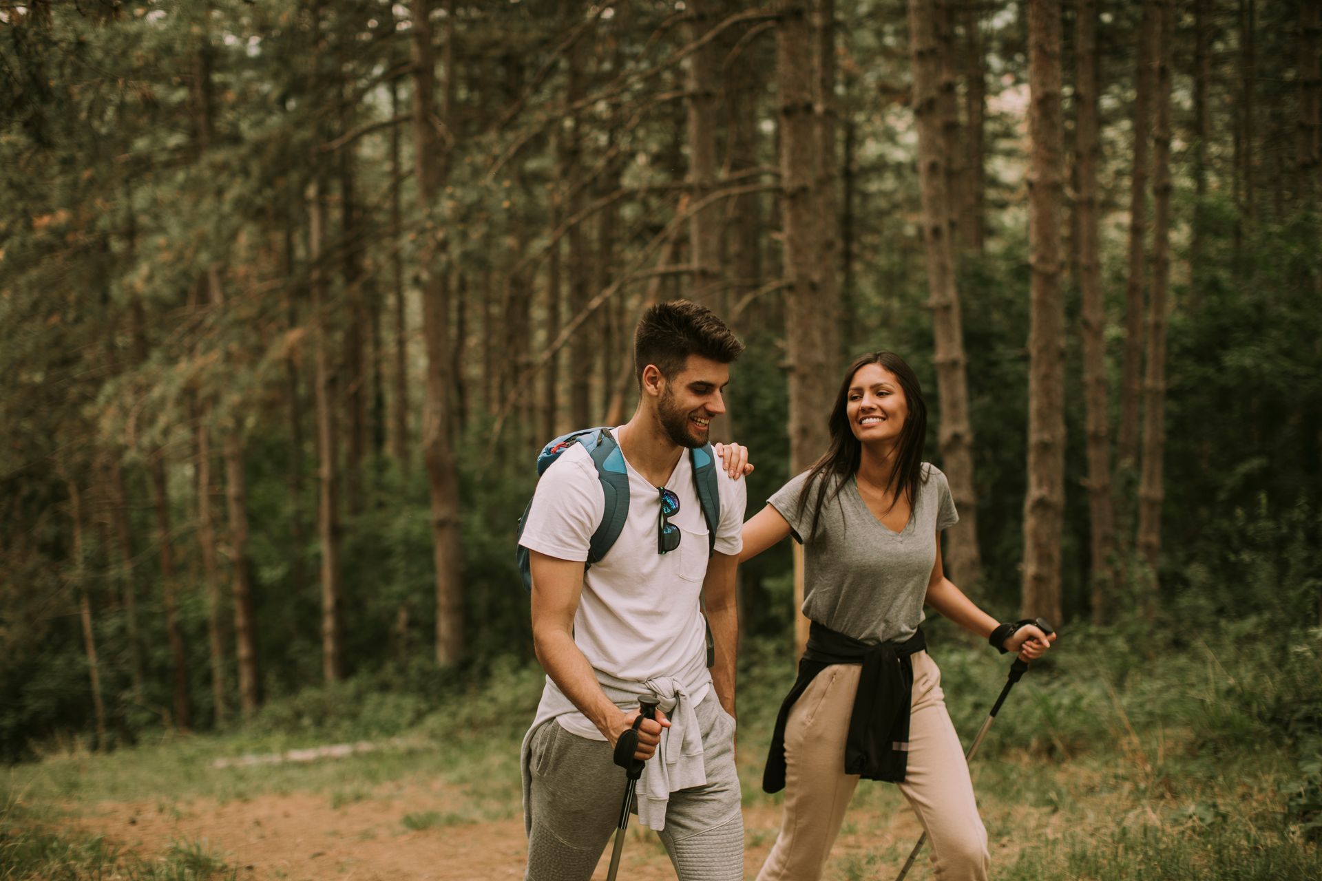 A man and a woman are walking through a forest.