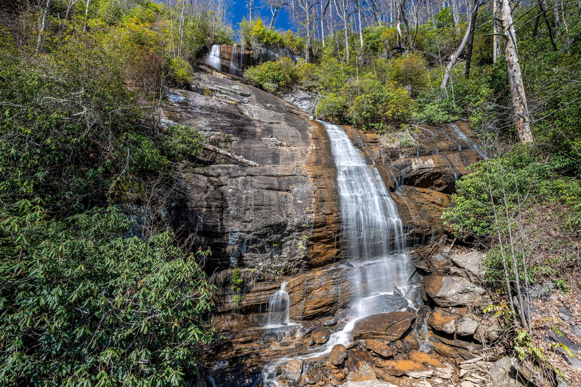 A waterfall is surrounded by trees and rocks in the middle of a forest.