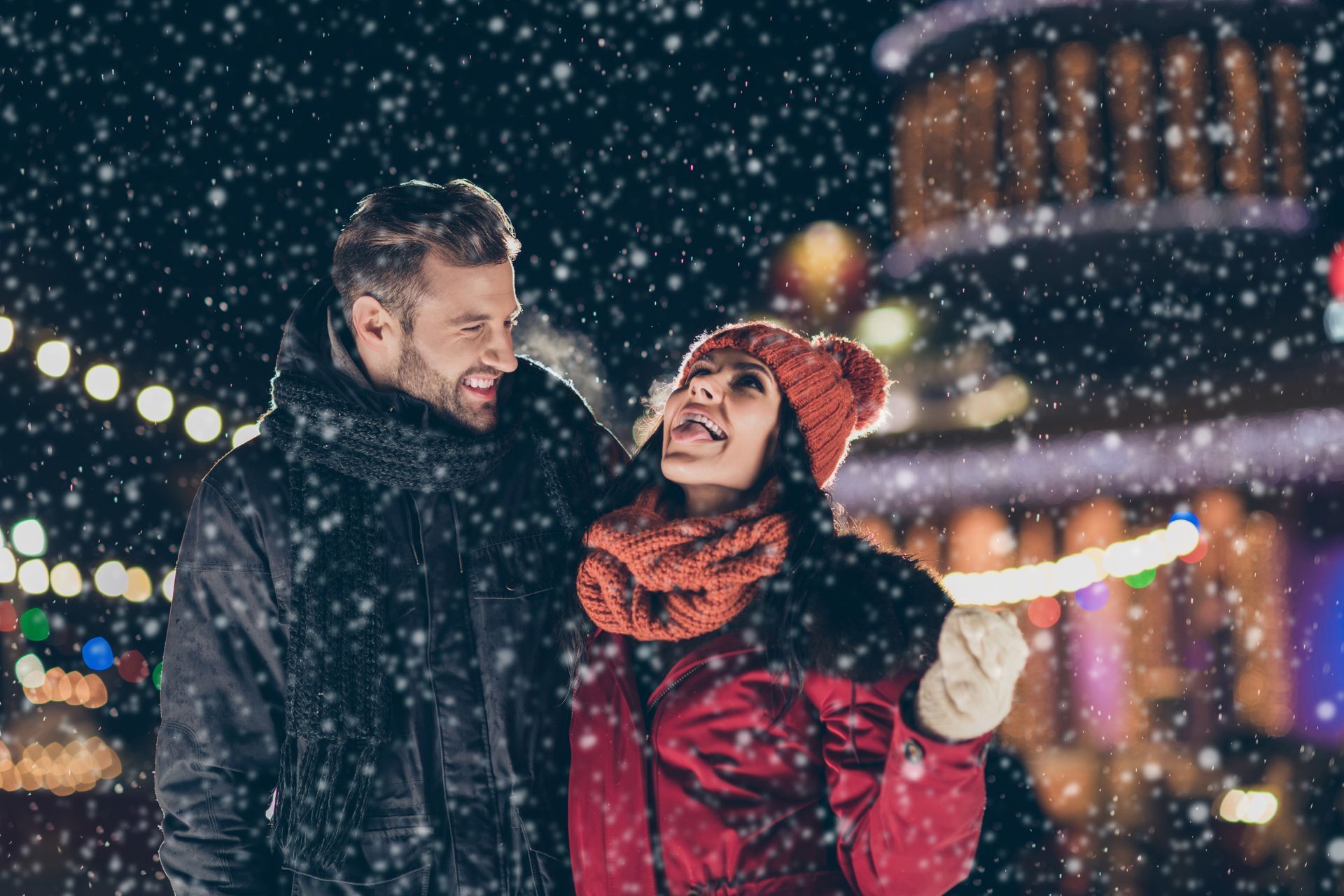 A man and a woman are standing in the snow looking at each other.