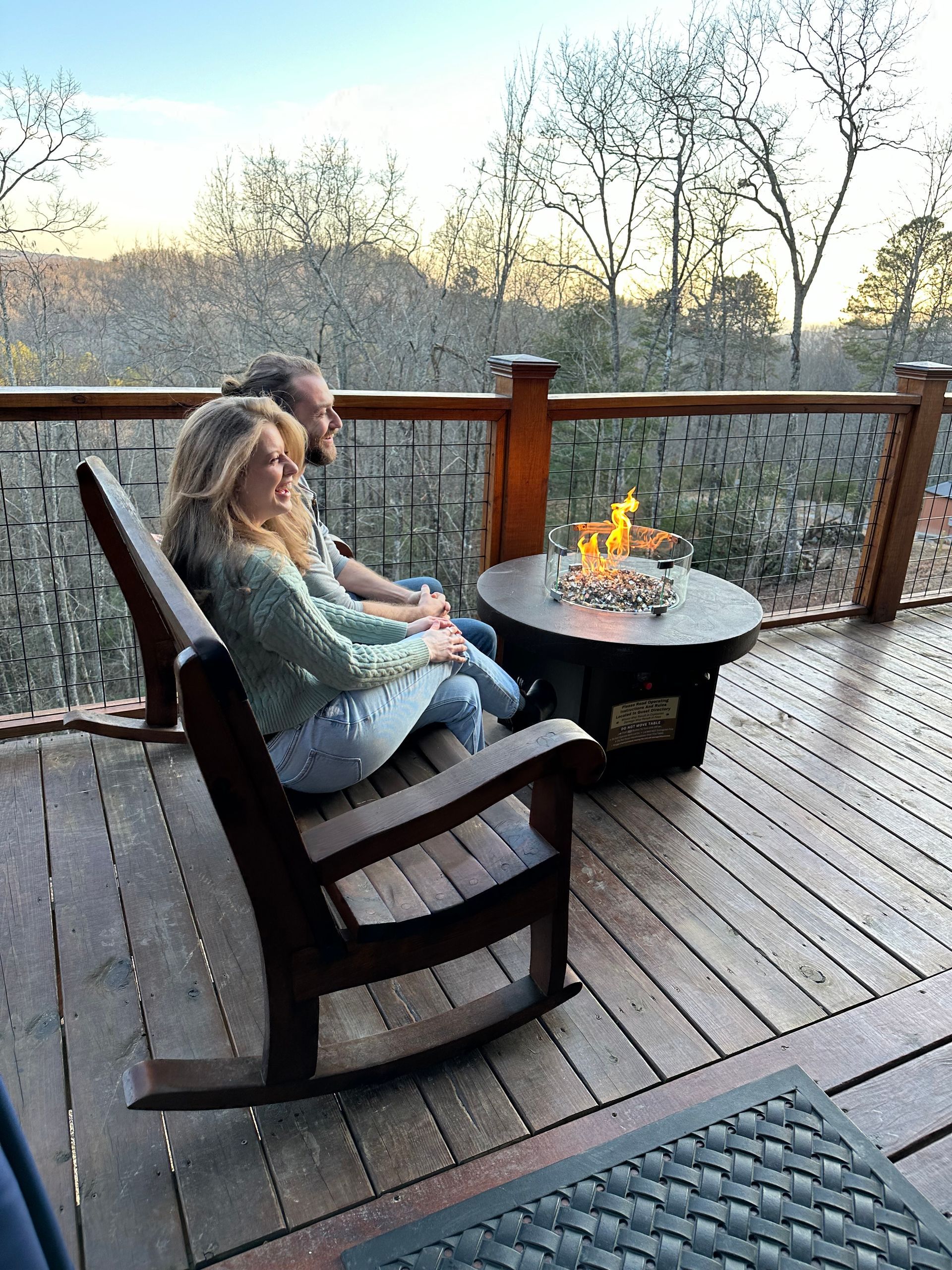 A man is kissing a woman on the cheek while they are sitting in front of a fireplace.