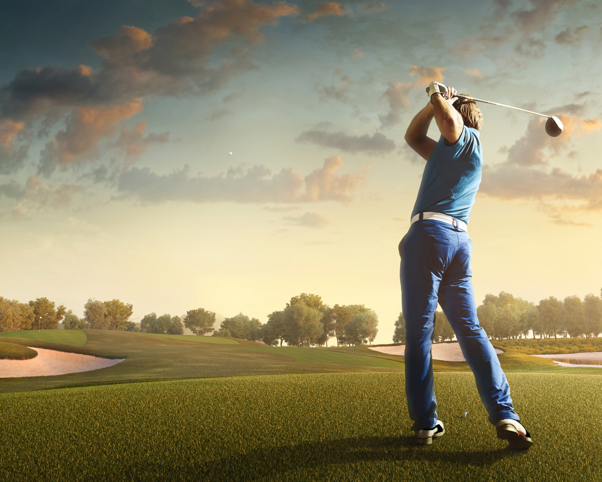 A man is swinging a golf club on a golf course.