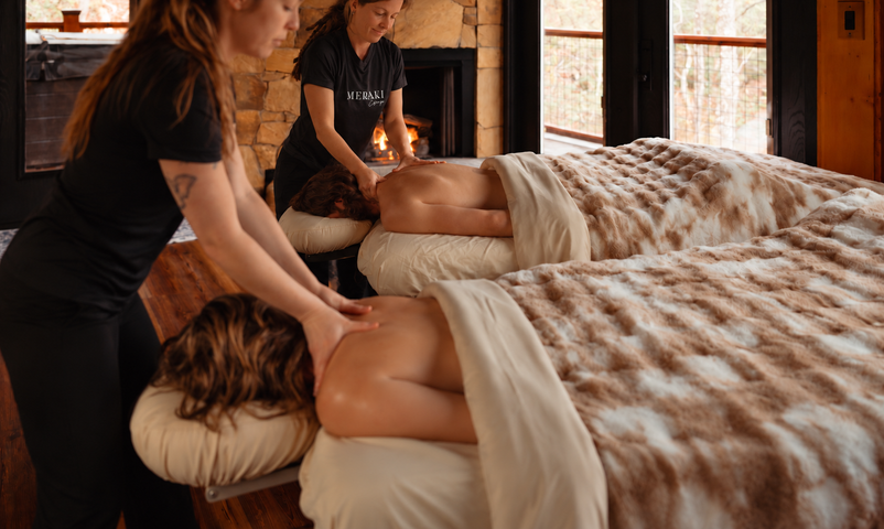 Couple receiving massages at a spa. Hands massaging their backs. Candles and a warm atmosphere.