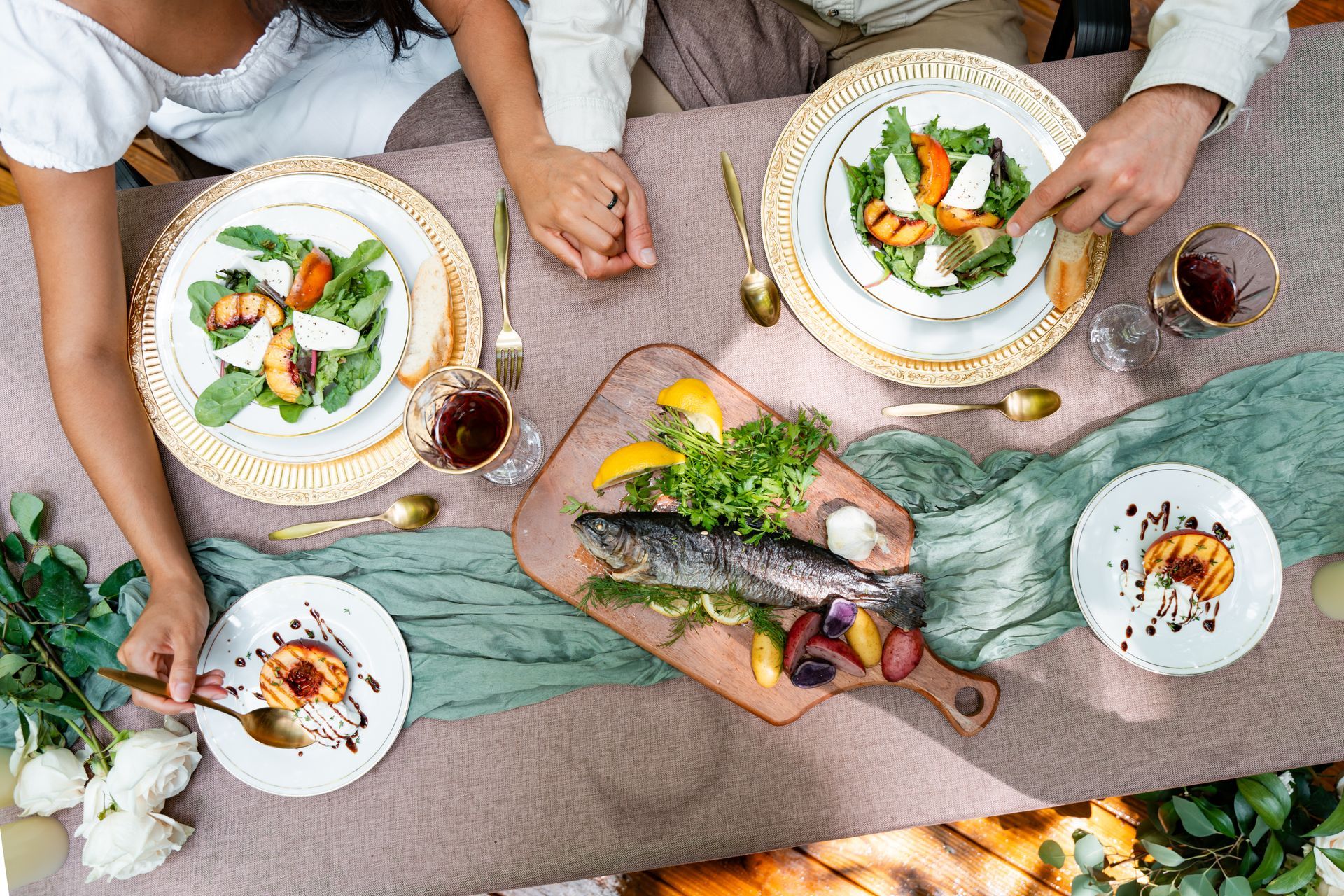 Two raw fish on a wooden cutting board with red onions, parsley, and rosemary on a rustic table