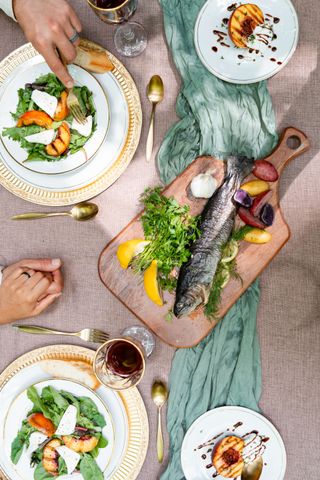 Couple holding hands over a delicious table of fresh seasonal food, outdoors.