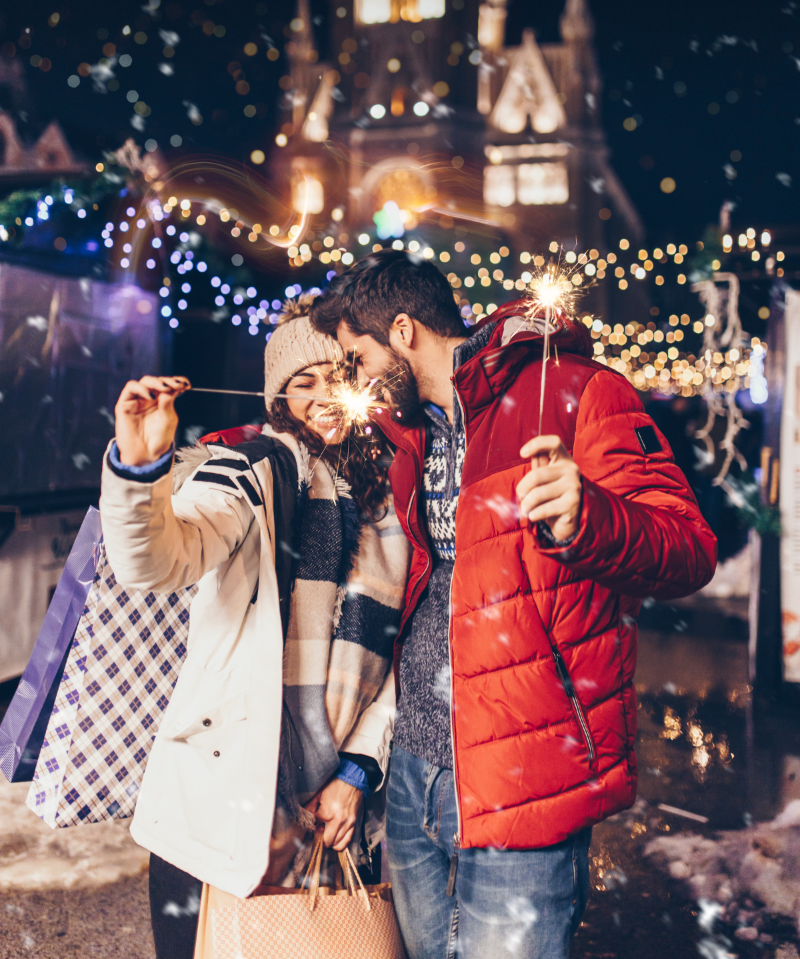 A man and a woman are holding sparklers and taking a selfie.