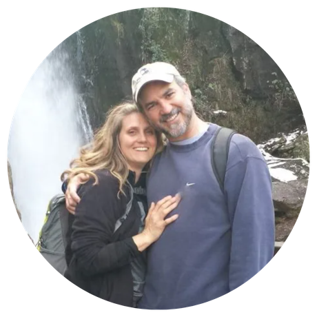 A man and woman are posing for a picture in front of a waterfall