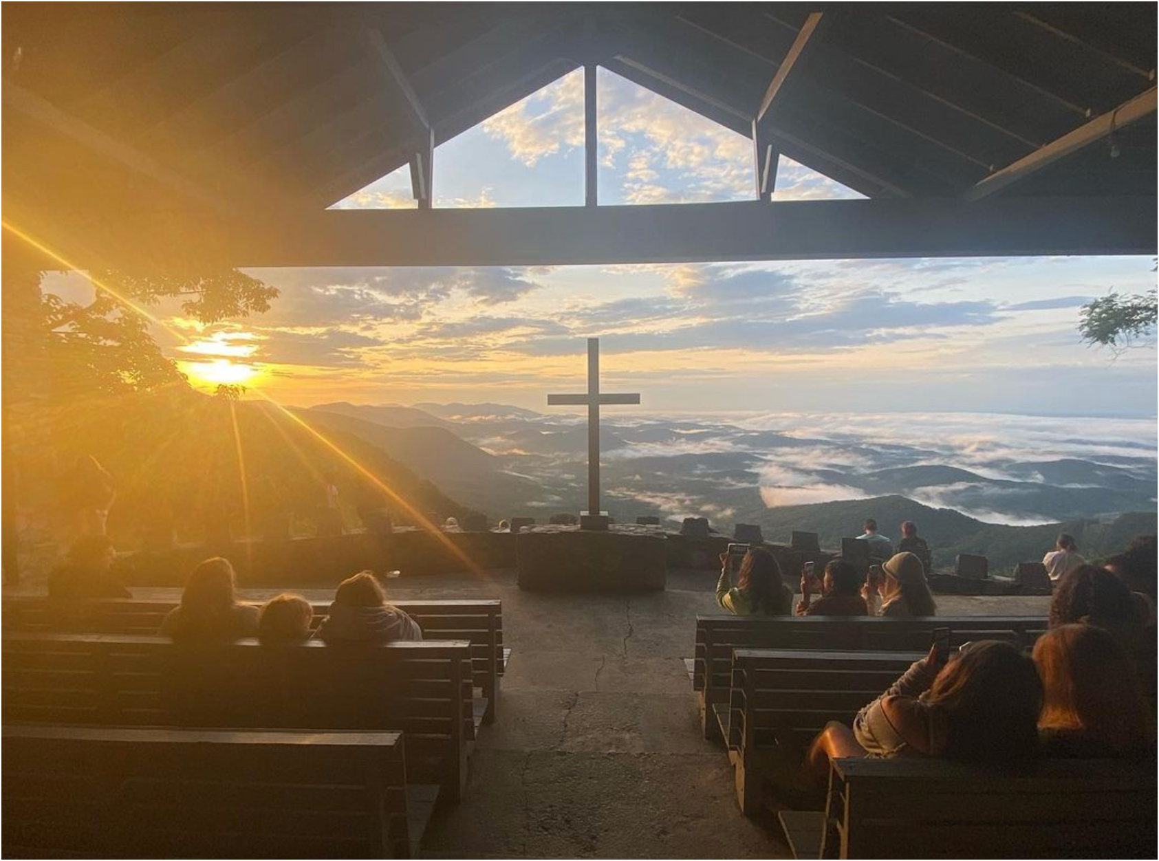 A group of people are sitting in a church with a cross in the background.
