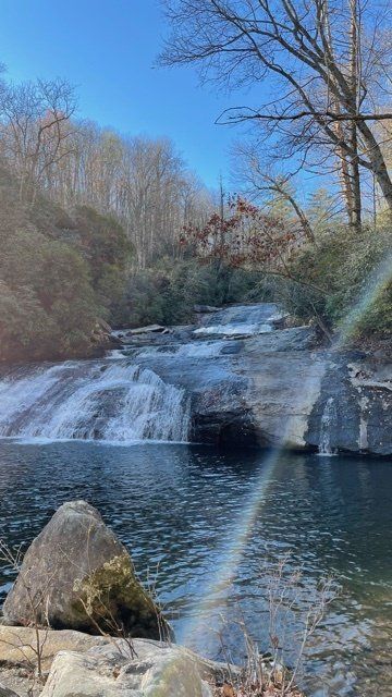 a waterfall in the middle of a forest with a rainbow in the water .