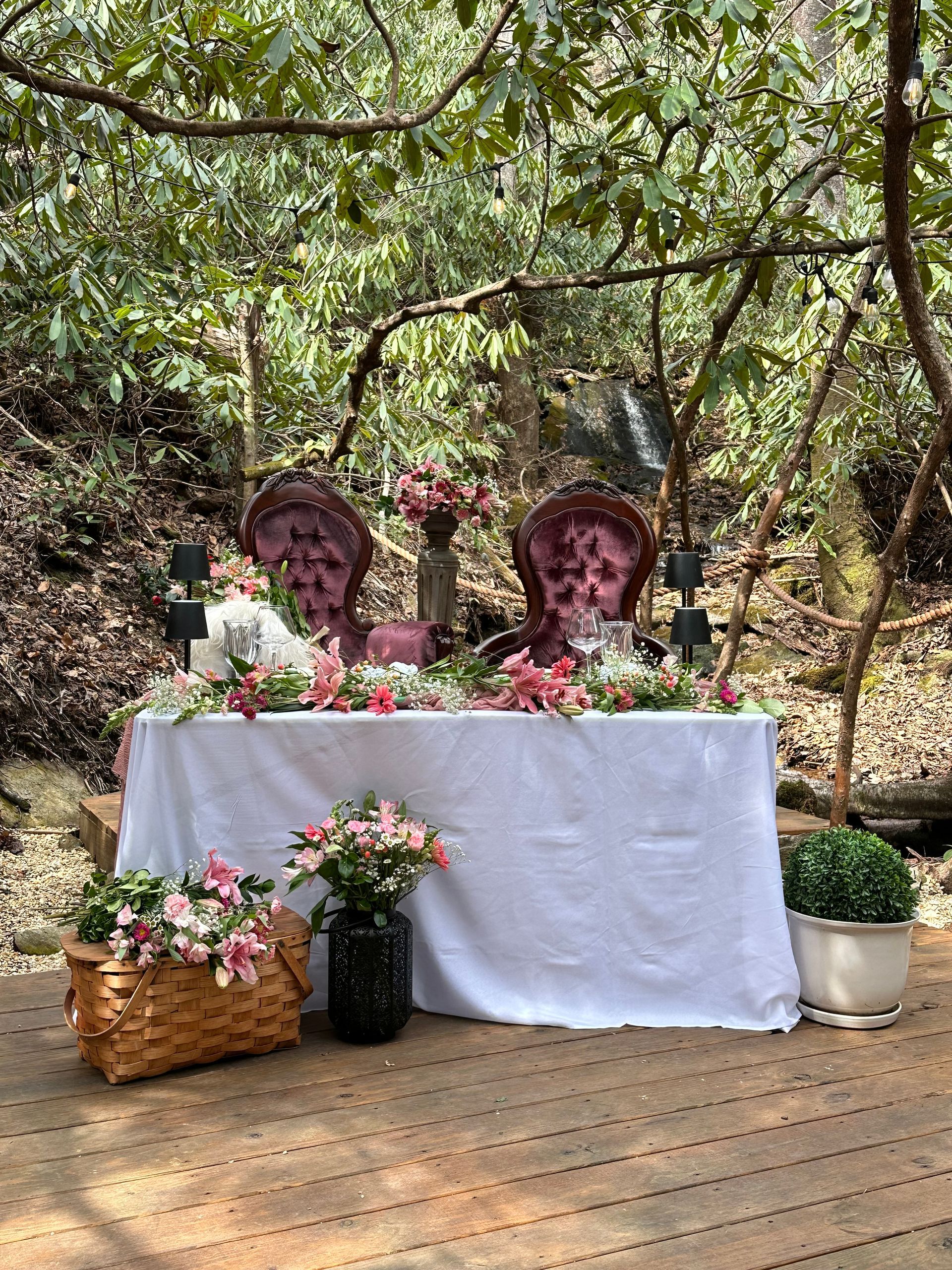 There is a table with flowers on it in the woods.