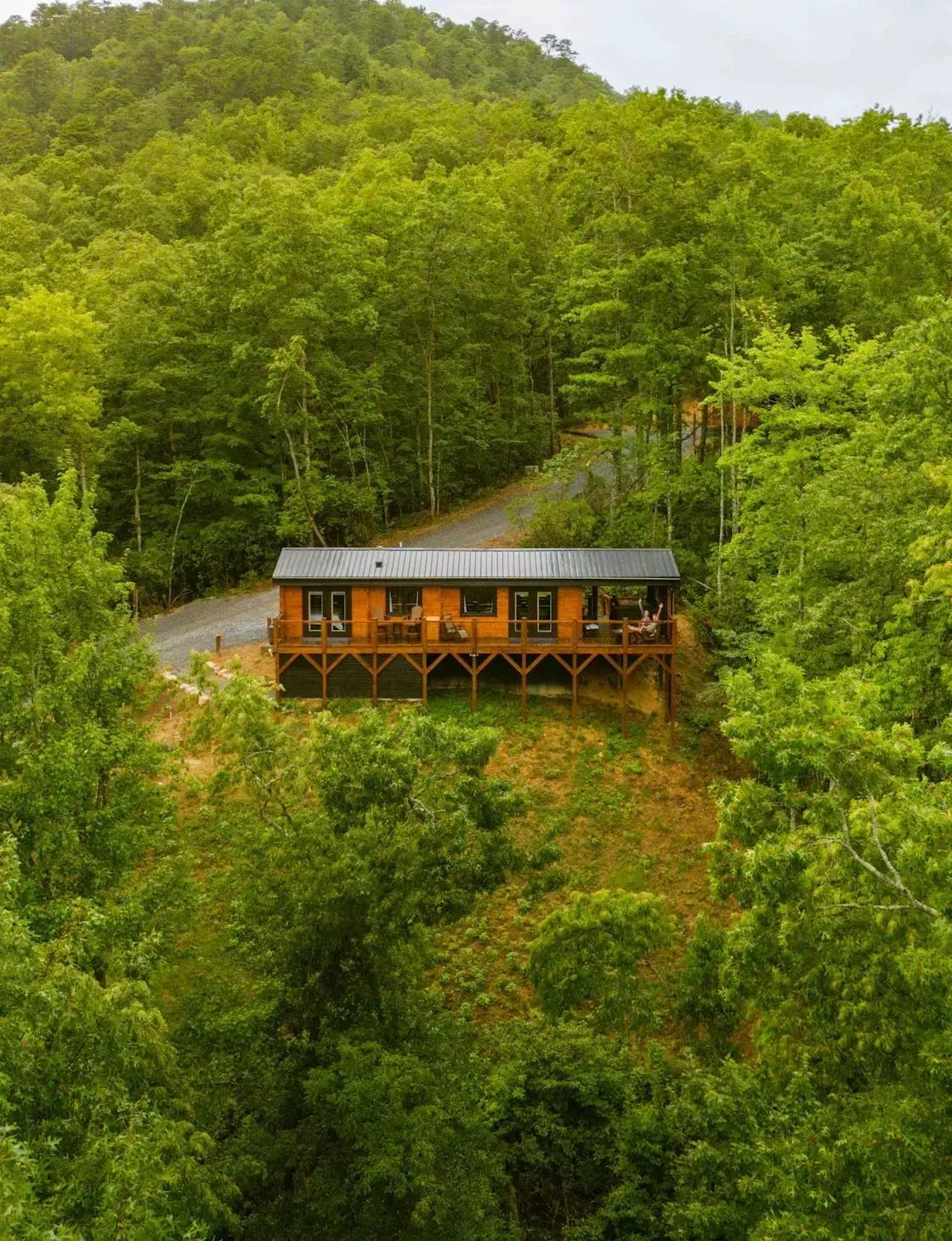 A small cabin is sitting on top of a hill in the middle of a forest.