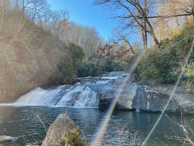 a waterfall is surrounded by trees and rocks in the middle of a forest .