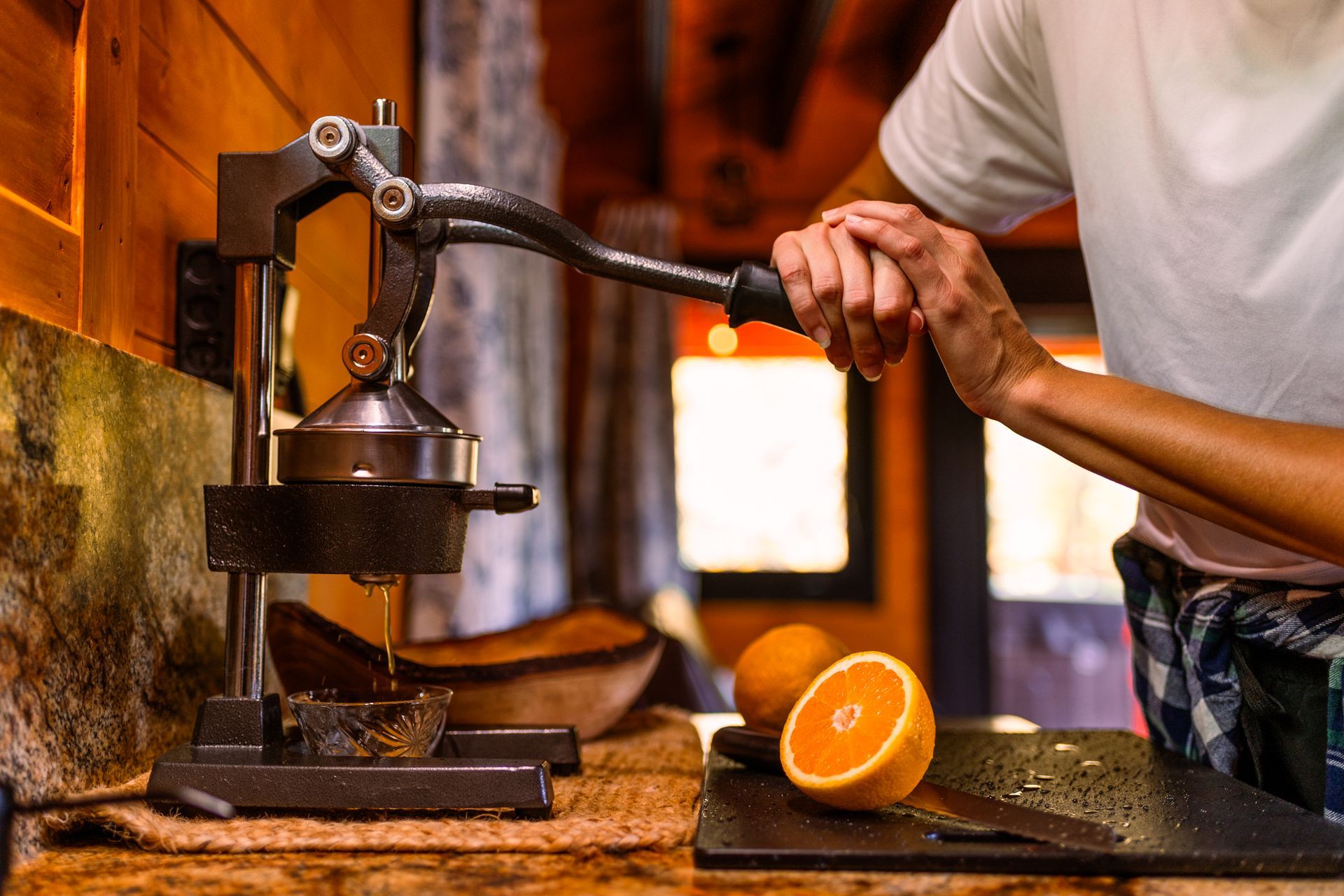 A person is squeezing orange juice from an orange press.