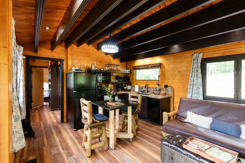 A living room with a couch , table , chairs and a refrigerator.