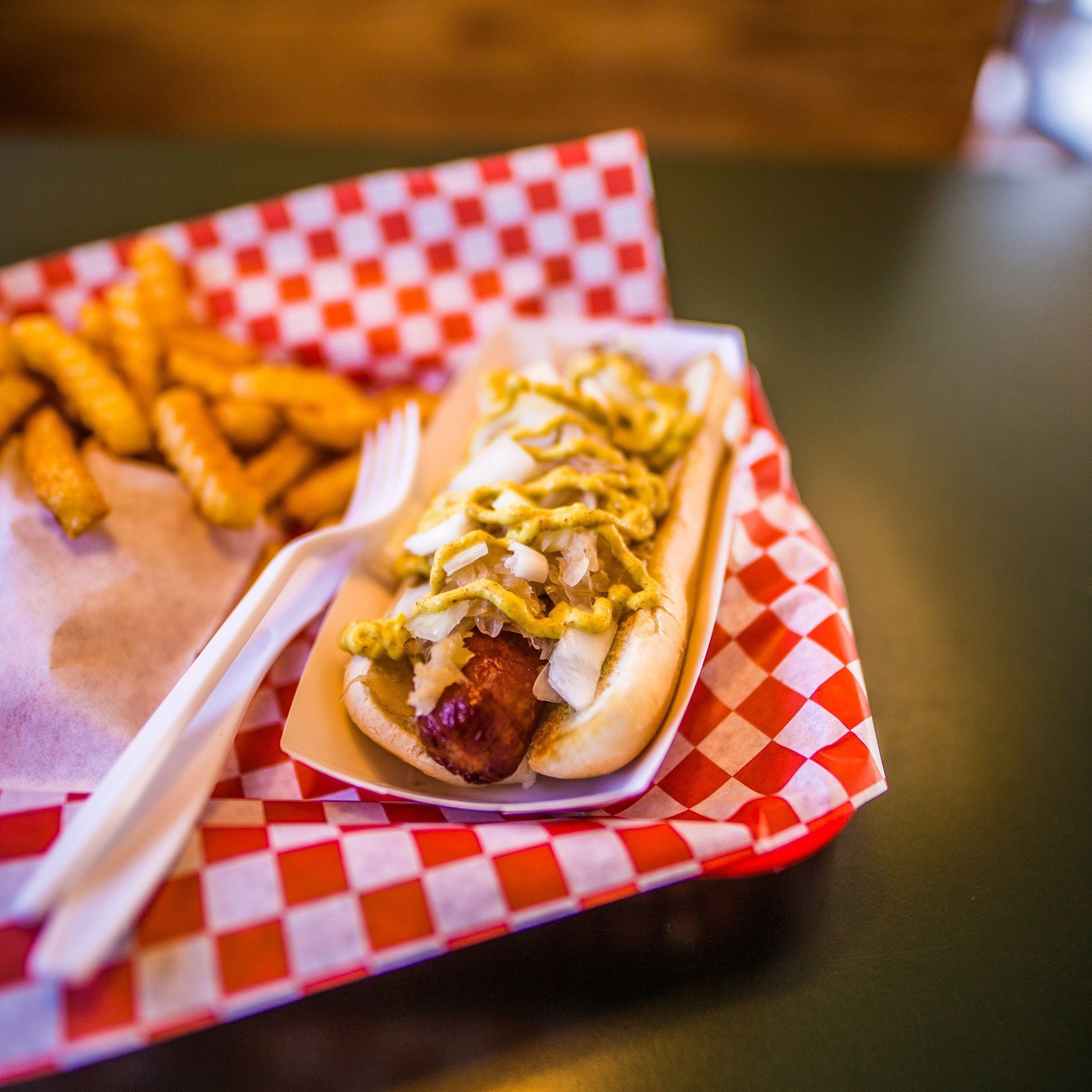 a hot dog and french fries on a checkered paper tray