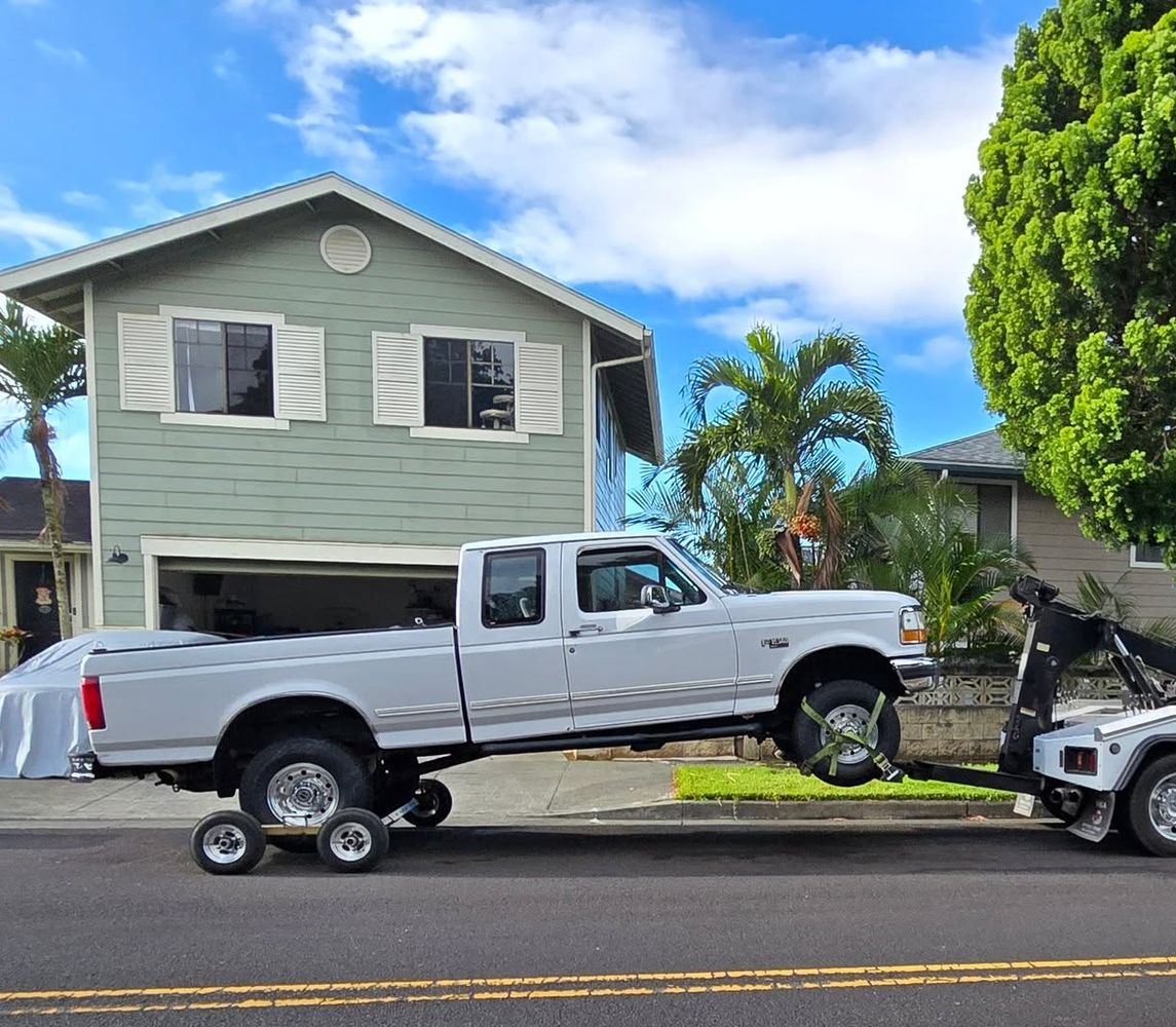 Two black pickup trucks parked side by side in a lot, with trees in the background.