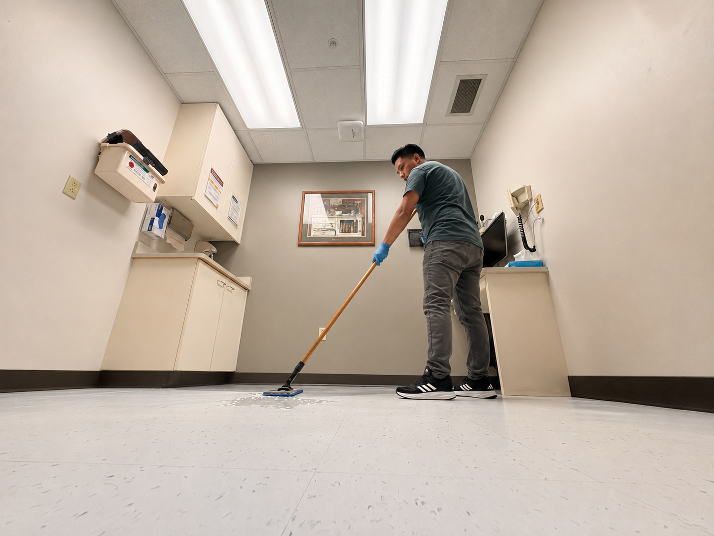 Person mopping a clean office floor in a bright room with cabinets and fluorescent lights