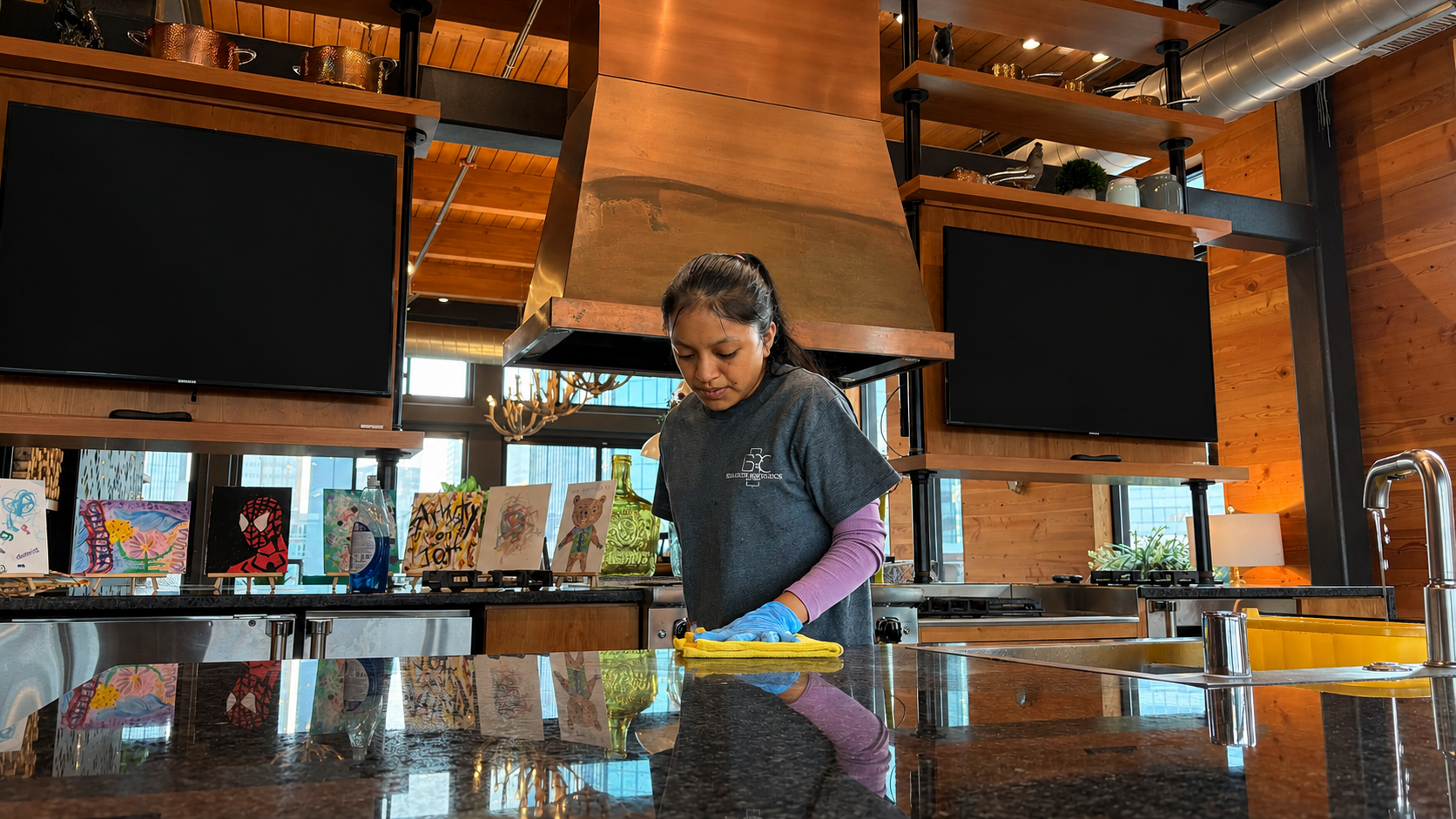 Person cleaning a glossy countertop in a warm restaurant or café interior