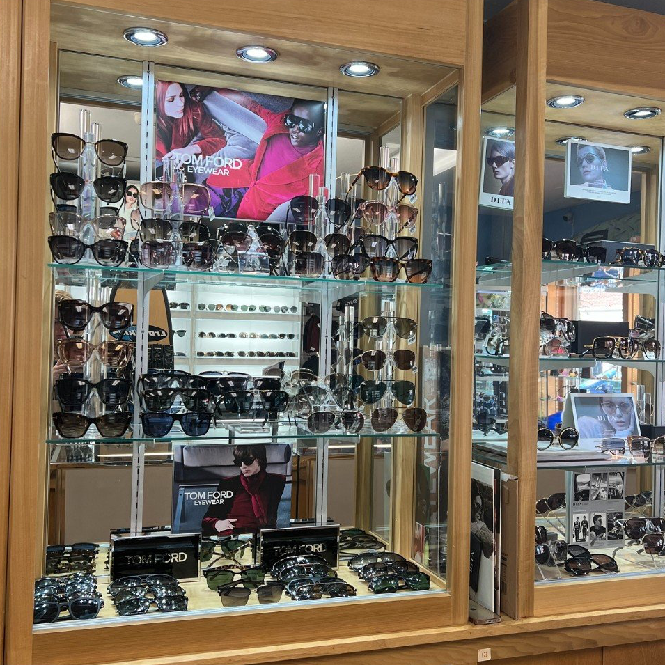 A display case filled with sunglasses and a poster for tom ford