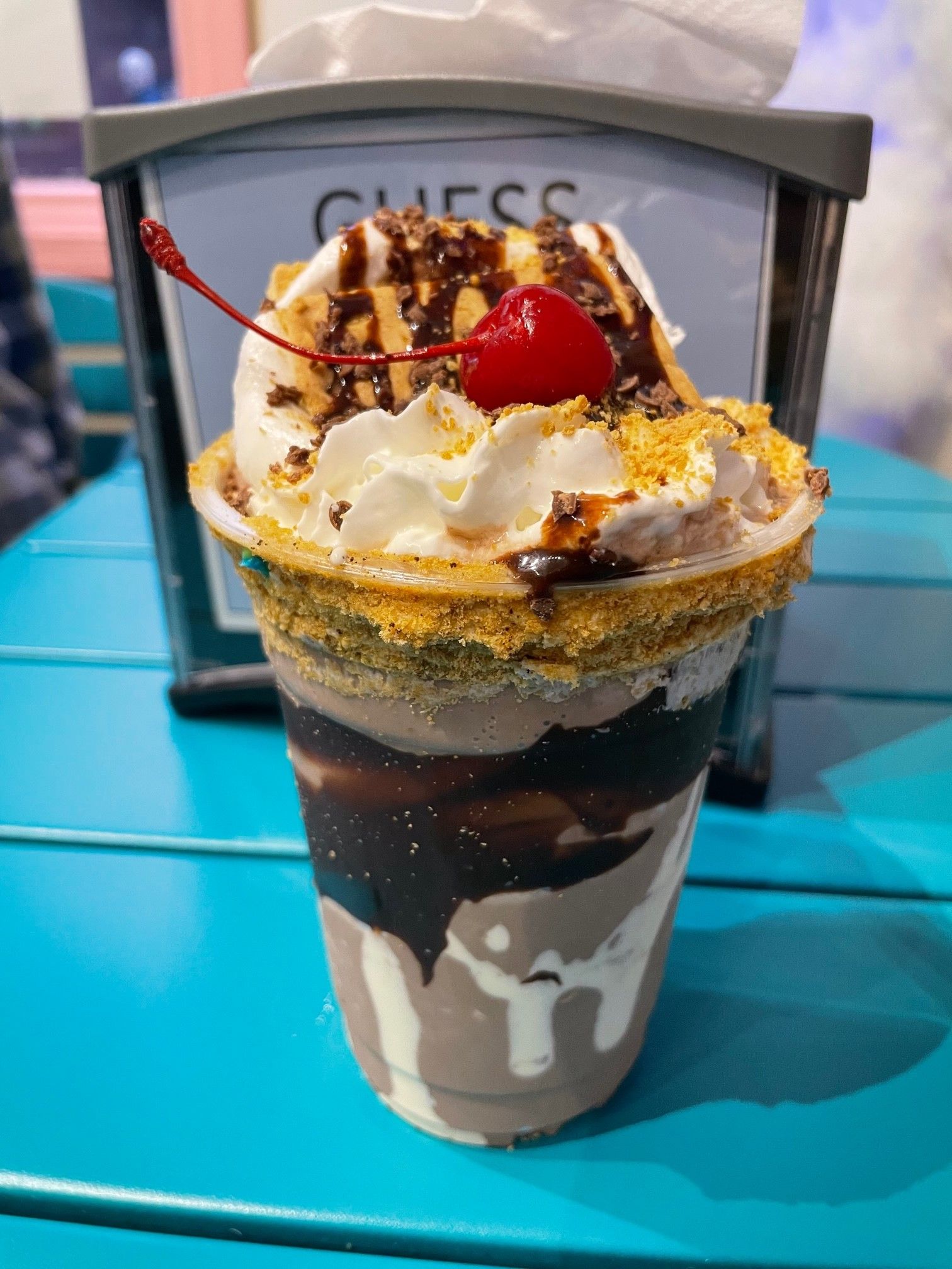 A cup of ice cream with whipped cream and a cherry on top