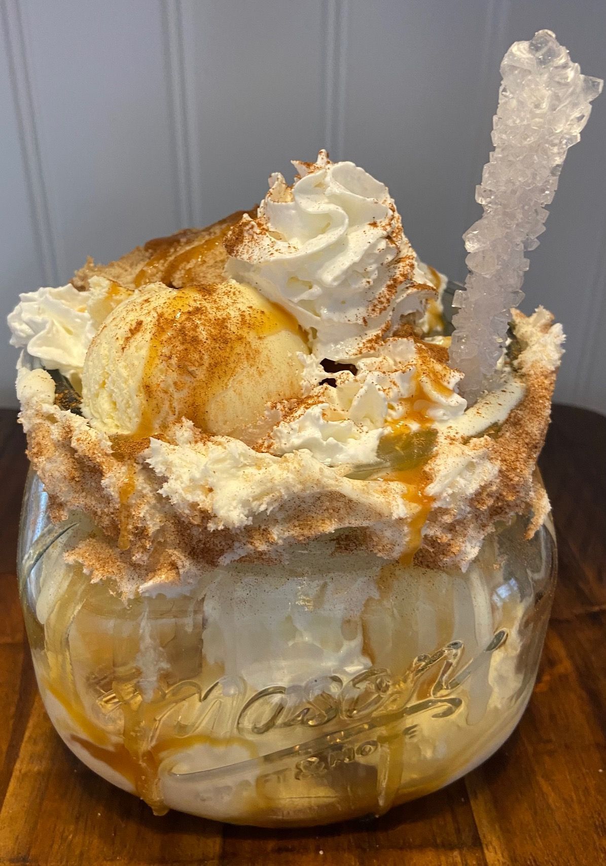 A close up of a dessert in a glass bowl on a wooden table.