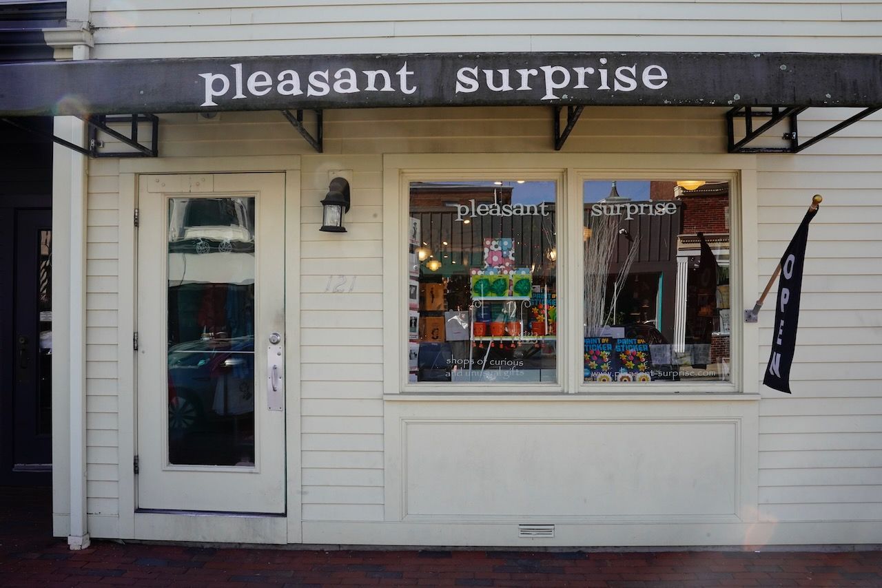 A white building with a black awning that says pleasant surprise.