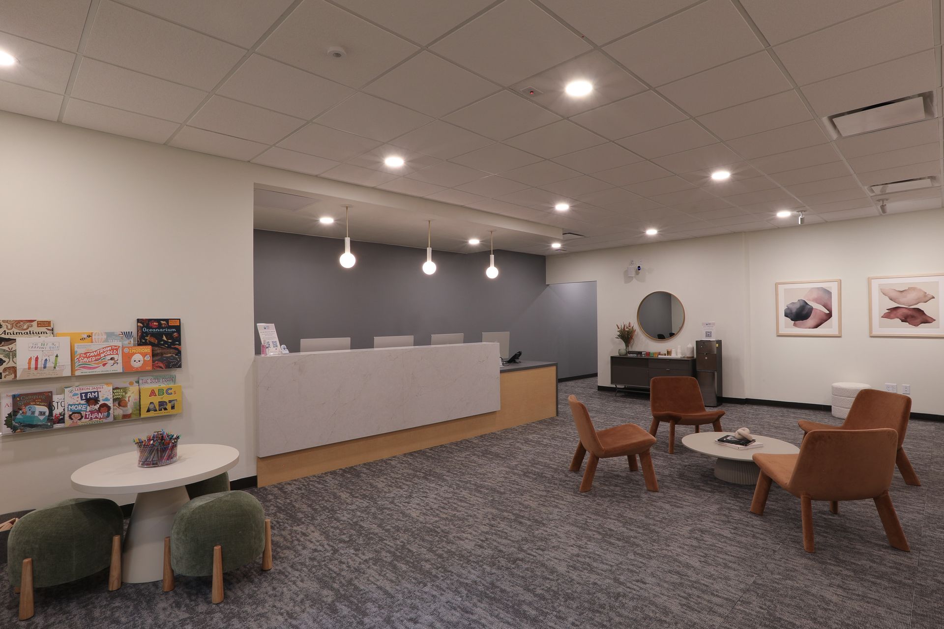 Reception area with white desk, seating, and a small bookshelf.